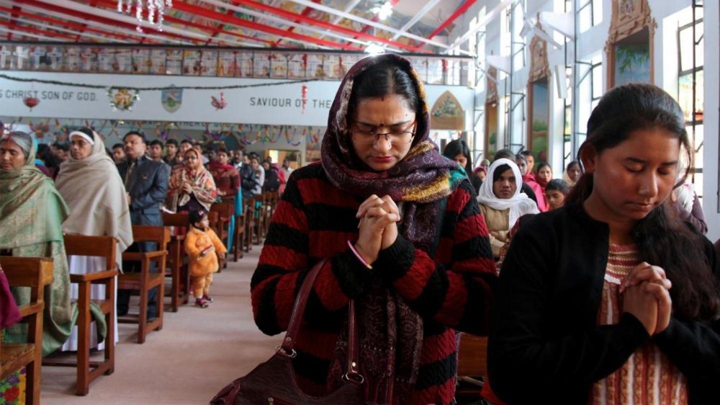 Famílias de cristãos perseguidos na Índia 2026 diante de casas destruídas.